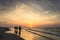 Riders on horseback riding along the seashore at sunset