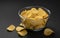 Ridged potato chips in glass bowl on black background
