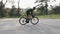 Riding a bicycle side follow view. Bearded man in black outfit on bicycle in the park. Out of the saddle pedaling. Slow motion