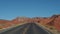 Riding On An Empty Road Leading To Red Mountain Rocks Buttes In Desert Valley