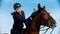 Riding a horse - young woman equestrian riding a brown horse