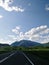 Riding mountain highway road with road sign full of greenery landscape in the sunny nature wildness under the blue skies and cloud