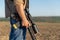 A rifle in a man& x27;s hand, close-up. Hunter with a weapon on the hunt against the background of a beautiful summer landscape