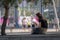 RIGA, LATVIA - JULY 18, 2018: A young woman sits on the bench at the edge of the street and looks at the phone.