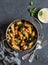 Rigatoni pasta with chickpeas, spinach and olives in a tomato sauce on a dark background, top view.