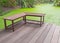 Right angle wood bench on veranda beside green pond of duckweed