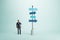 Right choice, dilemma and business strategy direction concept with pensive man in black suit looking at signpost with blue arrows