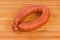 Ring of boiled-smoked sausage on a wooden surface