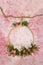 A ring of green twigs and pink roses hangs on a branch, for photos of newborn babies