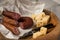 Ring Salami pork sausage with German BierbeiÃŸer and Edamer cheese in wax paper with knife on wooden board background for Brotzeit