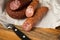 Ring Salami pork sausage with German BierbeiÃŸer in wax paper with knife on wooden board background for Brotzeit dinner