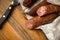 Ring Salami pork sausage with German BierbeiÃŸer in wax paper with knife on wooden board background for Brotzeit dinner