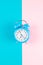 Ringing twin bell classic alarm clock isolated on blue and pink pastel colorful geometric background. Rest hours time of life good