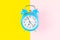 Ringing twin bell classic alarm clock isolated on yellow and pink pastel colorful geometric background. Rest hours time of life