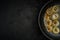 rings of fried onions in a metal frying pan on a black textured plaster surface. view from above. artistic dark moody food photo