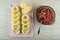 Rings of squash on cutting board, minced meat, spoon in bowl on wooden table. Top view