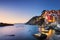 Riomaggiore town, cape and sea landscape at sunset. Cinque Terre, Liguria, Italy