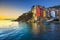 Riomaggiore town, cape and sea landscape at sunset. Cinque Terre National Park, Liguria Italy