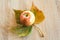 Ripe apple and autumn leaf on wooden background