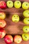 Ripe apples on a path laid out a framework and an apple with a smile on a wooden background.