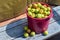 Ripe apples in a pink basket on bench under sunlight