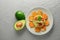Ripe avocado near plate with tasty guacamole and rusks on textured background