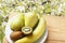 Ripe banana, kiwi fruit and pears on wooden table and on white flowers background in nature . Top view with copy space. Vegetarian