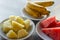 Ripe banana, pineapple and watermelon on white plates on table. Variety of tropical fruits. Exotic breakfast on tropical vacation.