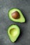 Ripe Beautiful Evenly Halved Organic Australian Avocado with Pit on Black Concrete Stone Background. Healthy Lifestyle Vegan