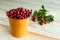 Ripe berries of lingonberry and blueberry in a decorative orange bucket on a wooden background.  Selective focus.