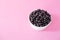 Ripe black currant or blueberries in a small white Cup on a pink background. Black currant harvest. Healthy food. vegetarian food