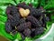 Ripe black mulberries fruit and one white in the shape of a heart on green mulberry leaf. Berry background. Close-up