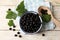 Ripe blackcurrants and leaves on light wooden table, flat lay