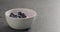 Ripe blueberries fall in blueberry yogurt in white bowl with copy space