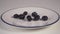 Ripe blueberries fall on a white plate with a blue border