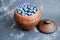 Ripe blueberries piled up in a clay, vintage pitcher, placed on a dark, gray background.