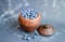 Ripe blueberries piled up in a clay, vintage pitcher, placed on a dark, gray background.