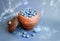 Ripe blueberries piled up in a clay, vintage pitcher, placed on a dark, gray background.