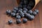 Ripe blueberries spilling from paper cup on wood table