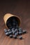 Ripe blueberries spilling from paper cup on wood table
