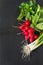 Ripe bunch red radish, onion, parsley with foliage on a black dish as background. Top view. Ingredients for salad.