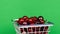 Ripe cherries in a metal basket rotate. Green background.