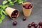 Ripe cherries in paper cups. Mint leaves on table