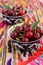 Ripe cherry in oriental bowls on bright ethnic fabric