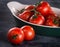 Ripe cherry tomatoes in a bowl on a black background.