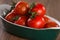 Ripe cherry tomatoes in a bowl on a wooden table.