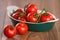 Ripe cherry tomatoes in a bowl on a wooden table.