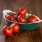 Ripe cherry tomatoes in a bowl on a wooden table.