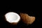 Ripe coconut is broken into two halves isolated on a black background close-up. the insides of the tropical palm fetus