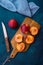 Ripe colorful red and yellow nectarines, halved on wood cutting board, knife, blue napkin